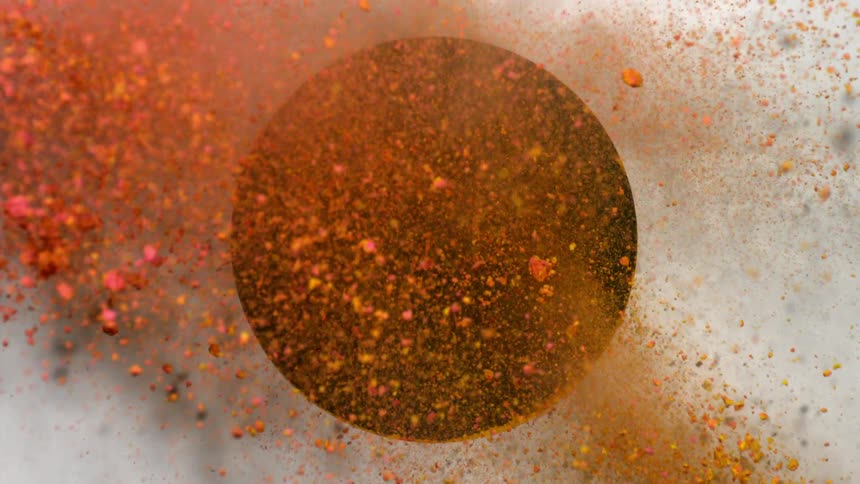 Yellow and pink powders collide as they are shot through a circle in a panel