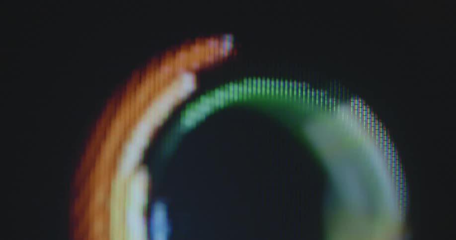 Shaky handheld dynamic extreme macro footage of a rainbow colored multilayered circle in LGBT colors moves around somewhat chaotically on a screen symbolising diversity and the fight and protest for homosexual rights and gender equality