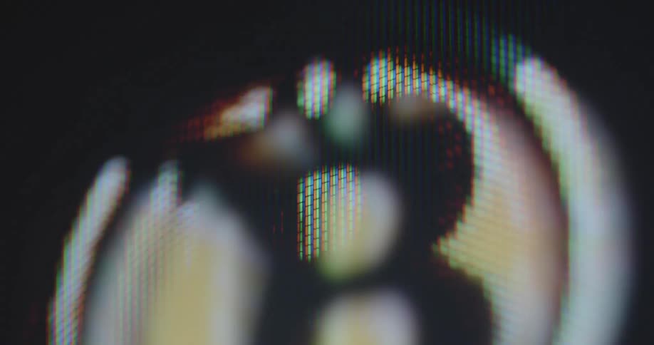 Extreme macro close up of a Bitcoin or BTC symbol that flashes on a smartphone screen with pixels representing the power of crypto mining and blockchain technology as the future of the worldwide and global financial system