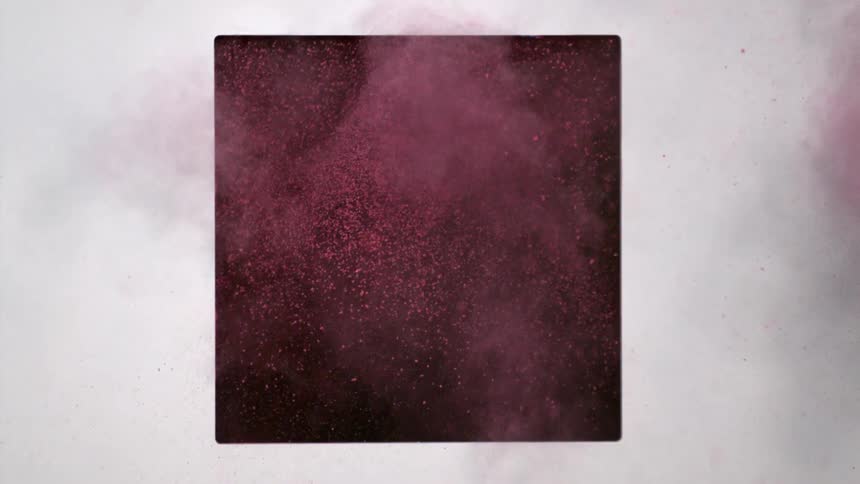 Pink dirt flies out of a black square