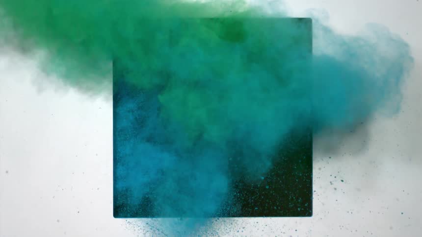 Green and blue powders are blowing through a dark opening in a panel