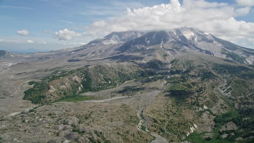 Approaching Mount St Helens with clouds capping the peak showcasing the breathtaking beauty of Washington's Cascade Mountains during a partly cloudy day