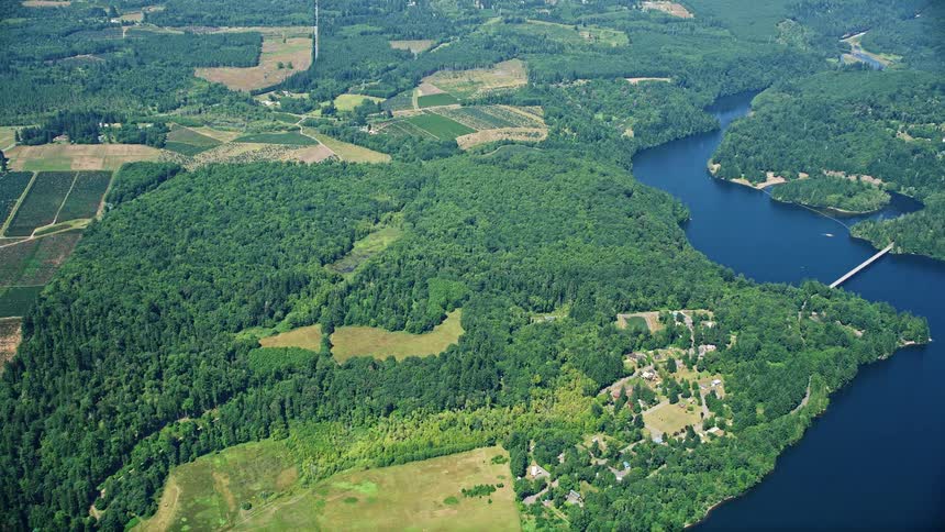 Aerial footage showcasing the scenic beauty of farms fields and Mayfield Lake in Silver Creek Washington during a sunny summer day