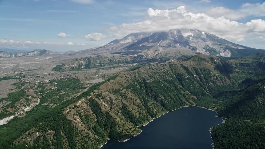  aerial footage showcasing the breathtaking landscape of Castle Lake and Mount St Helens in Washington as the camera flies over the lake and approaches the majestic mountain peak on a partly cloudy day