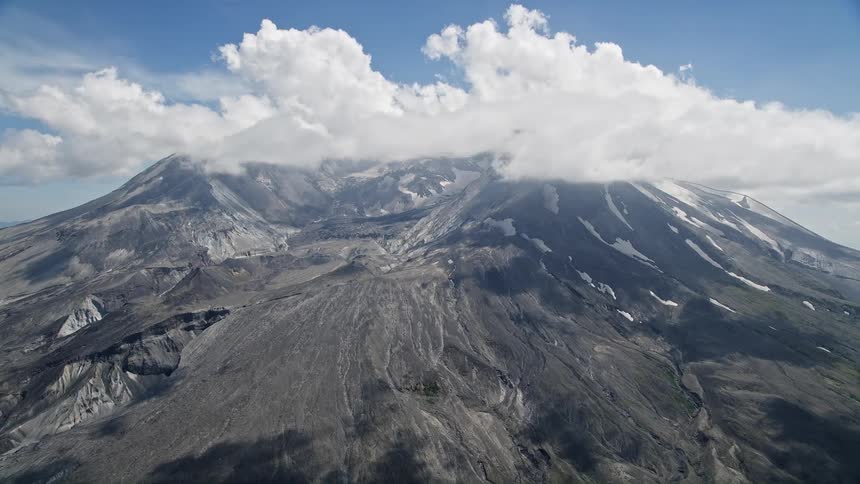 Aerial footage of Mount St Helens crater and cloud cover during a sunny day in Washington's wilderness