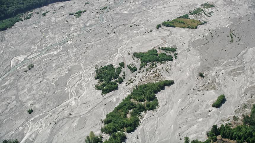 Aerial footage capturing the reverse view of the sediment-filled North Fork Toutle River in Washington during a sunny day in summer