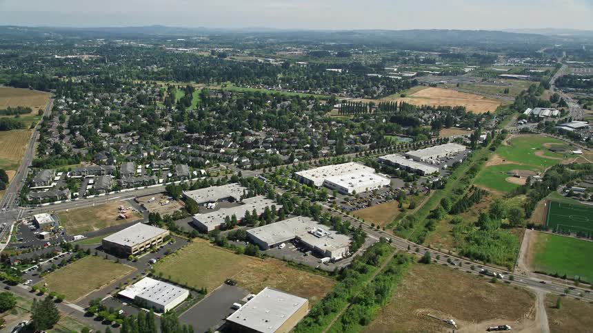 Aerial footage of a sunny suburban neighborhood in Hillsboro Oregon with office buildings across the street