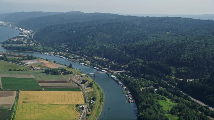 Aerial footage of a bridge spanning the Multnomah Channel surrounded by crop fields and meadows in Riverview Oregon
