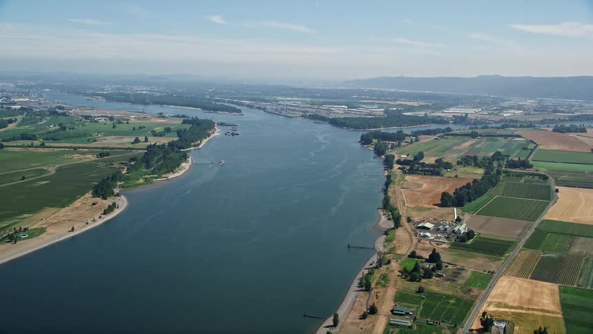 Aerial view of Columbia River flowing between Washington and Oregon farmland showcasing sunny day scenery and wide-angle perspective