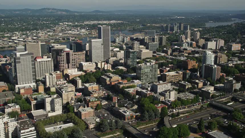 Aerial view of Downtown Portland Oregon showcasing the city buildings skyscrapers and Interstate 405 with heavy traffic during daylight hours in the summer