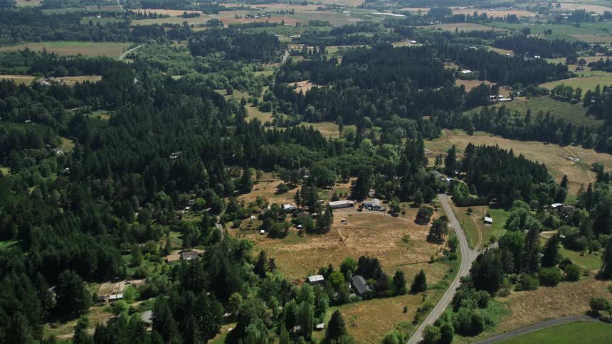 Aerial view of countryside in Hillsboro Oregon with farms residential homes and forests along a country road during a sunny day in summer