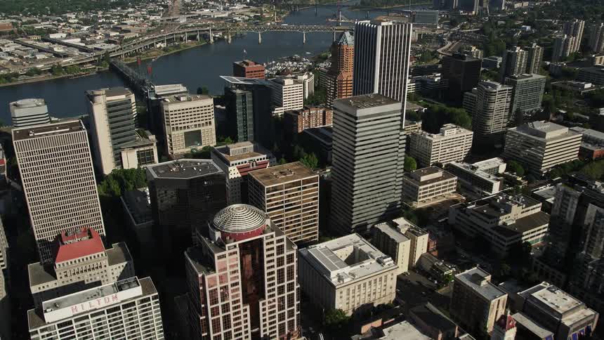 Aerial footage soaring over the downtown area of Portland Oregon capturing the vibrant cityscape of skyscrapers including an impressive view of the KOIN Center