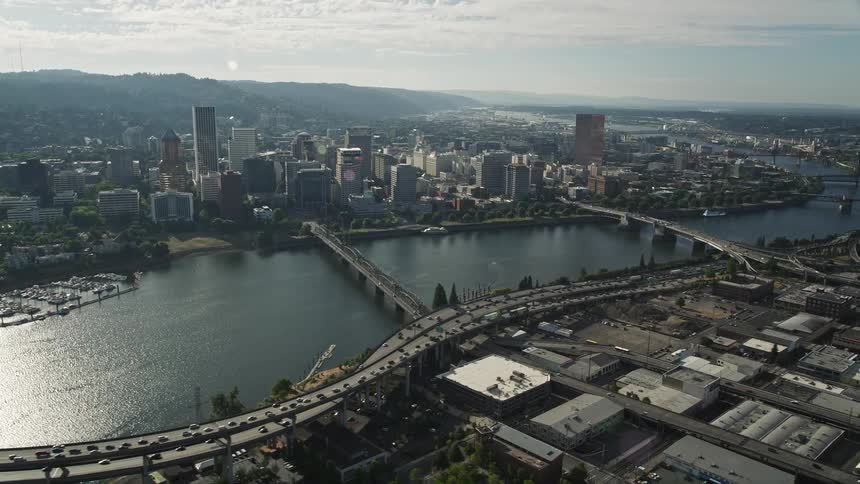 Aerial view of downtown Portland buildings and bridges with cars moving along the Willamette River on a sunny day in the summer
