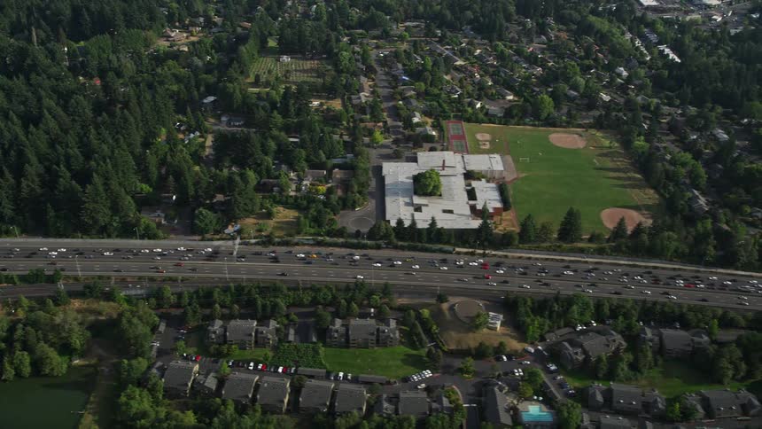 Aerial view of heavy traffic on a busy highway passing by a school park and baseball field in Southwest Portland Oregon