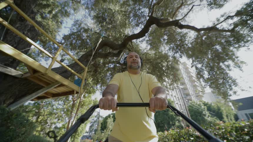 Man wearing headphones mowing the lawn outside during day time