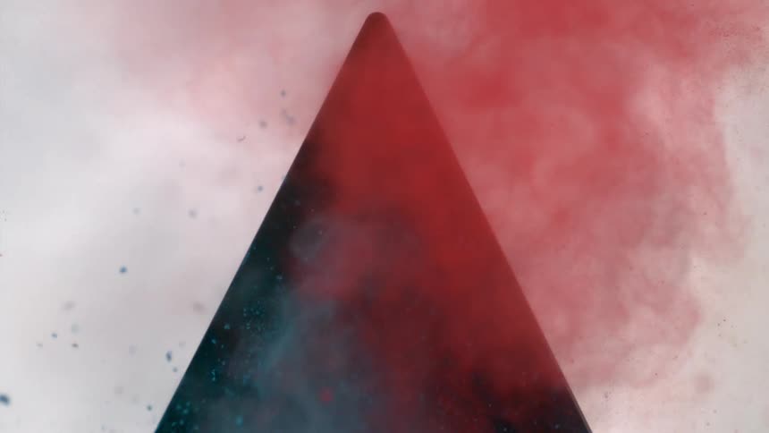 Red dust and green dust blow out of a triangular opening in a wall