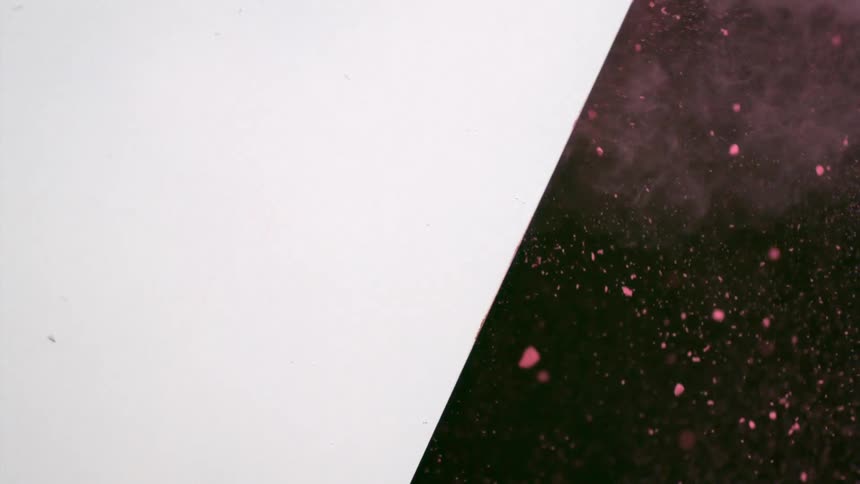 Pink powder blows out of a hole in a wall
