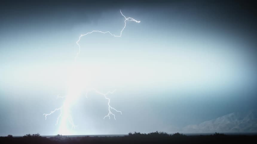 In the cold dark night lightning strike reveals the surrounding trees around the environment