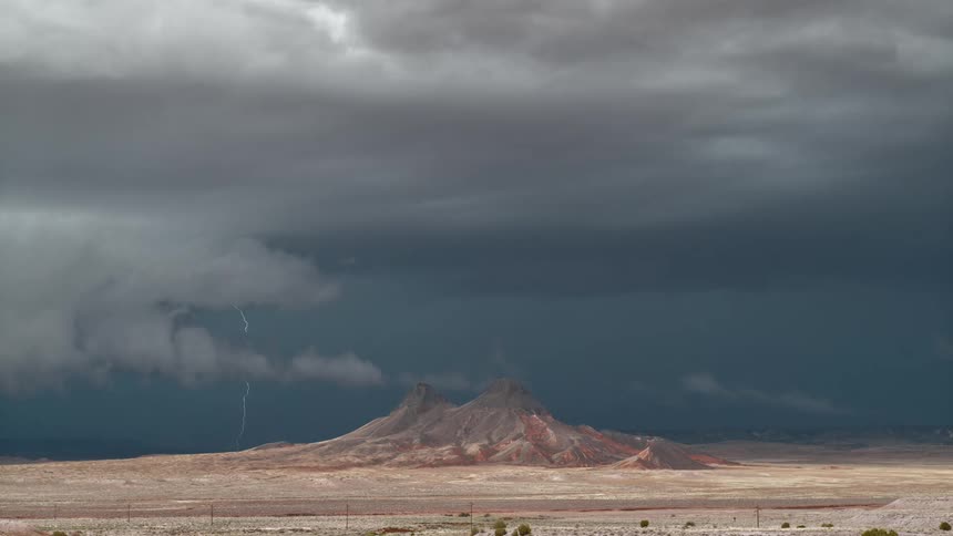 A dark and stormy sky in a desert that has a few craggy hills