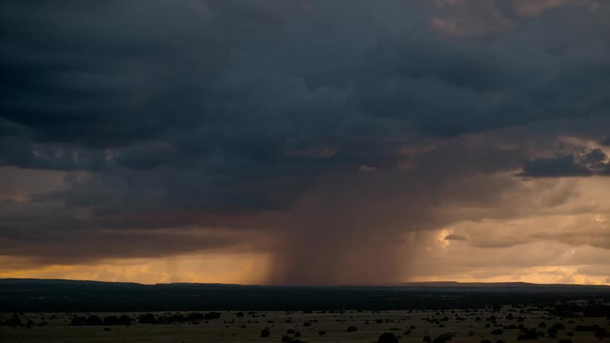 A sequence of bright lightning strikes across a deserted field in the midst of a thunderstorm