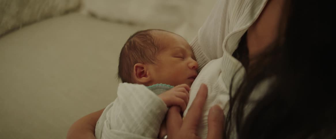 A woman hugging a newborn baby while rocking it in her lap