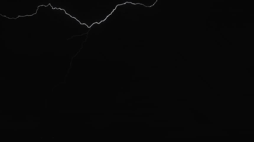 A lightning storm at night lighting up the night sky showing power lines and clouds in the sky