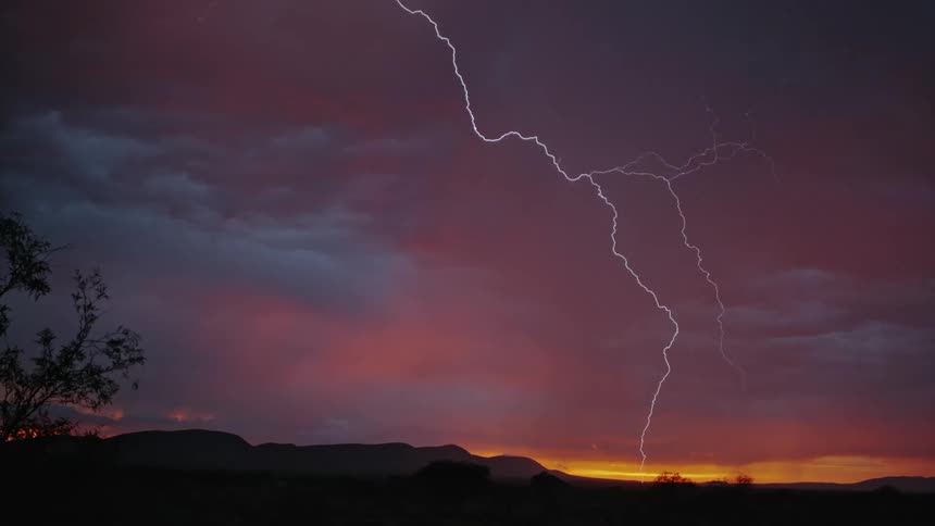 Bolts of lightning streak through the cloudy sky at sunset