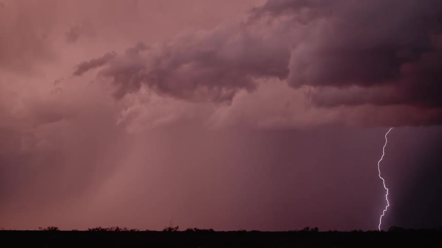Lightning flashes across a dark pink sky and strikes the ground