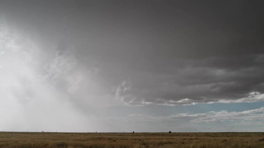 Lightning striking down in the middle of the day on a wide open field on a bright day