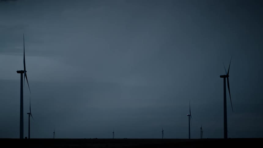 A field with several wind turbines and lightning falling in the sky