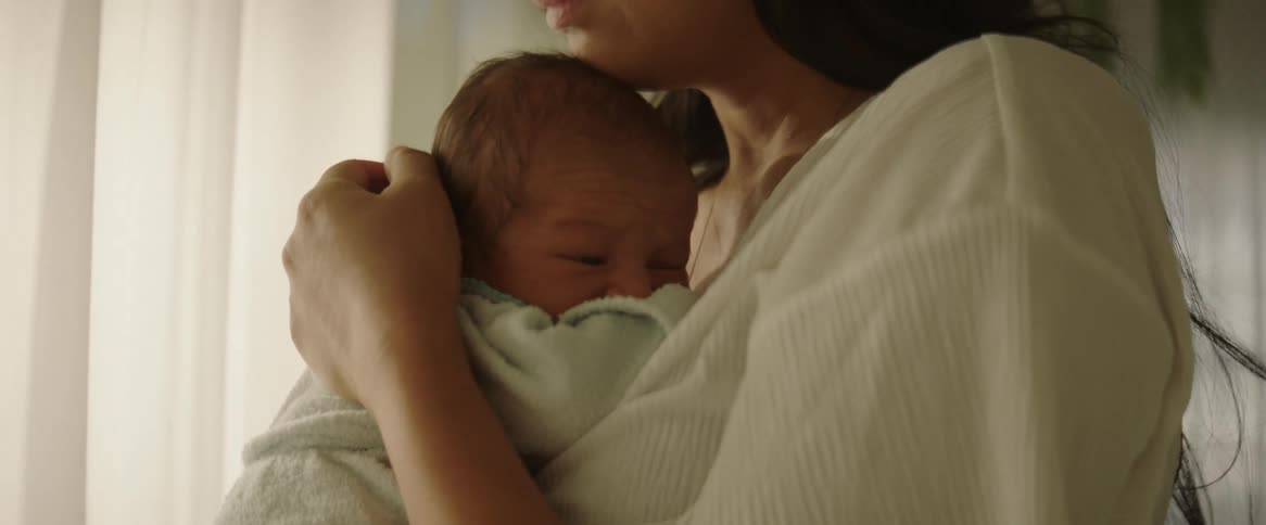 A mother is holding her son by the window