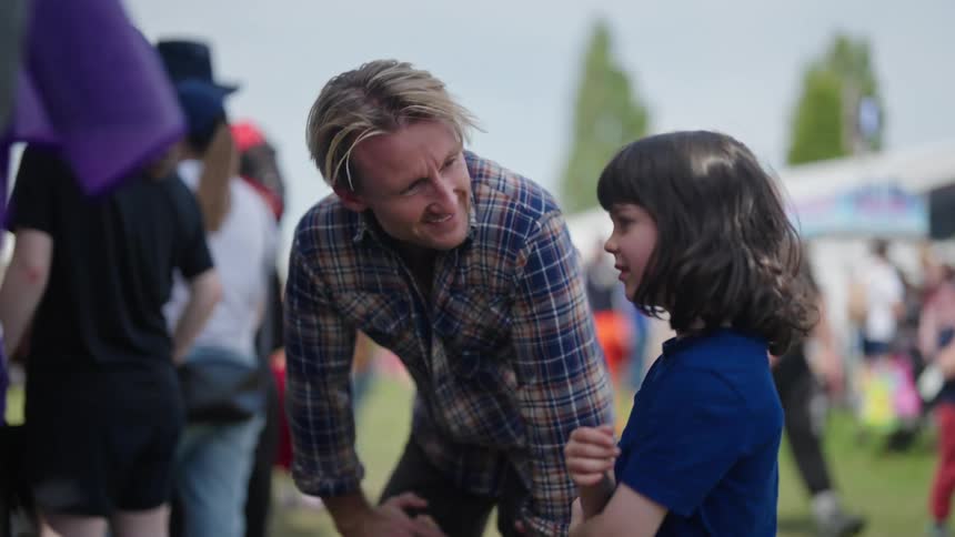 A father is talking to his daughter at the town fair