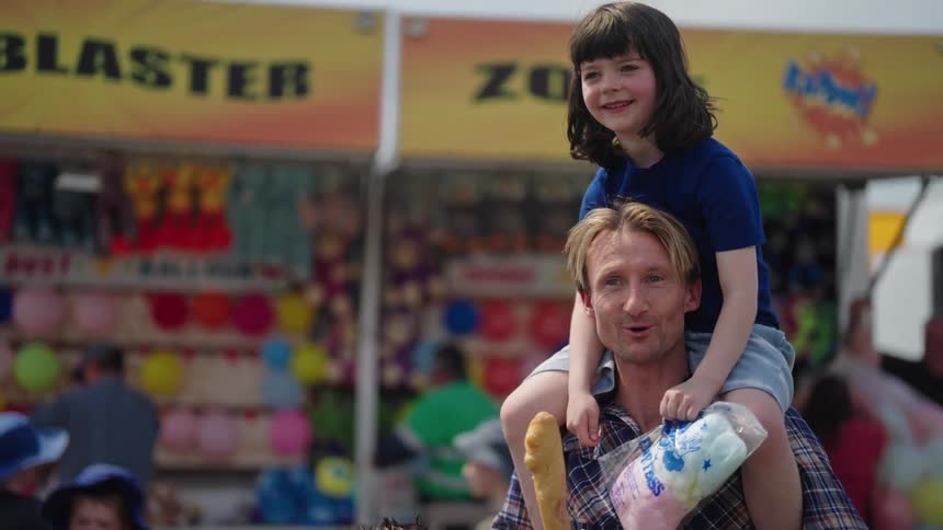 Father carrying his daughter on his shoulders happy and smiling