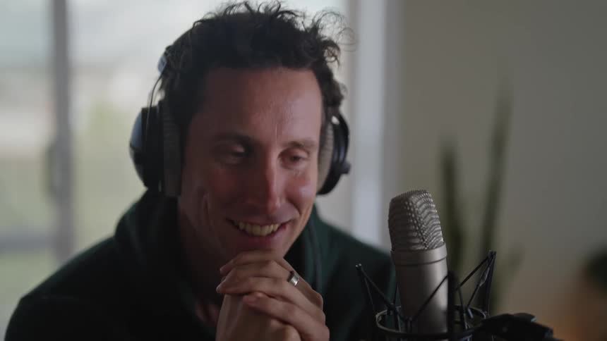 A man smiling while wearing heaphones and wiggling your chin