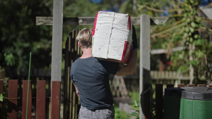 A man is carrying a box into the garden