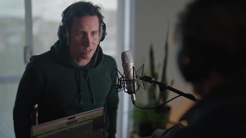Two people putting on headphones and talking on a podcast