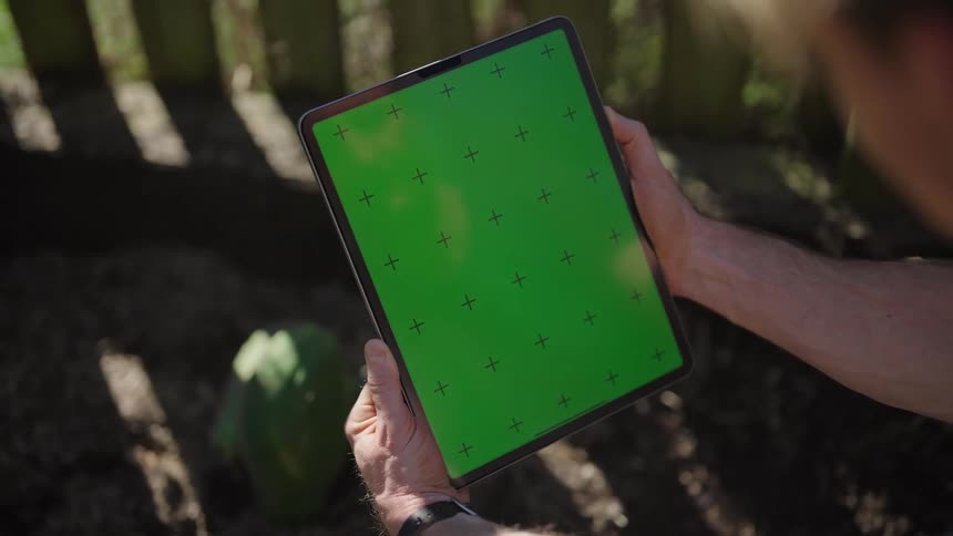 A man is sitting outside while staring at a tablet with a replacement screen