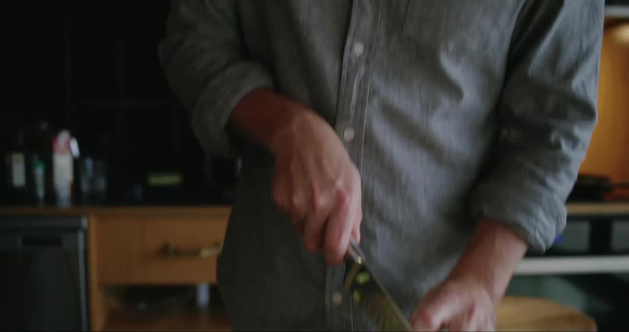 A man cuts celery with a knife on a cutting board