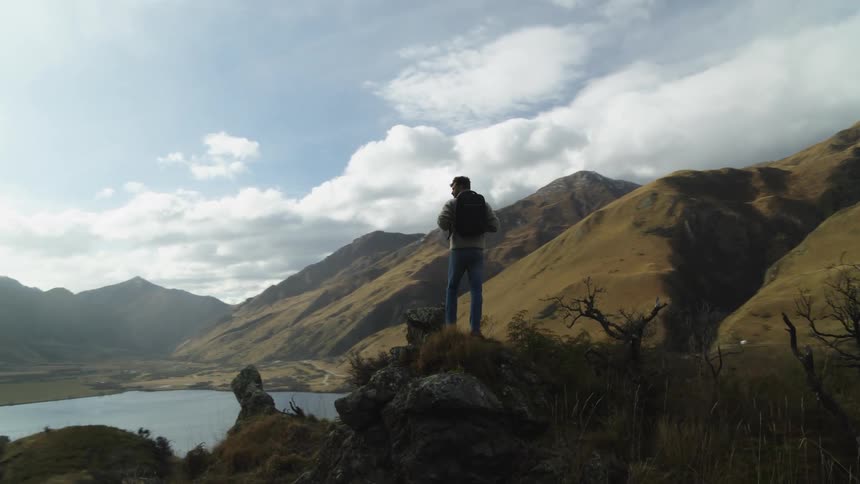 Man on a mountain watching the landscape with a lake