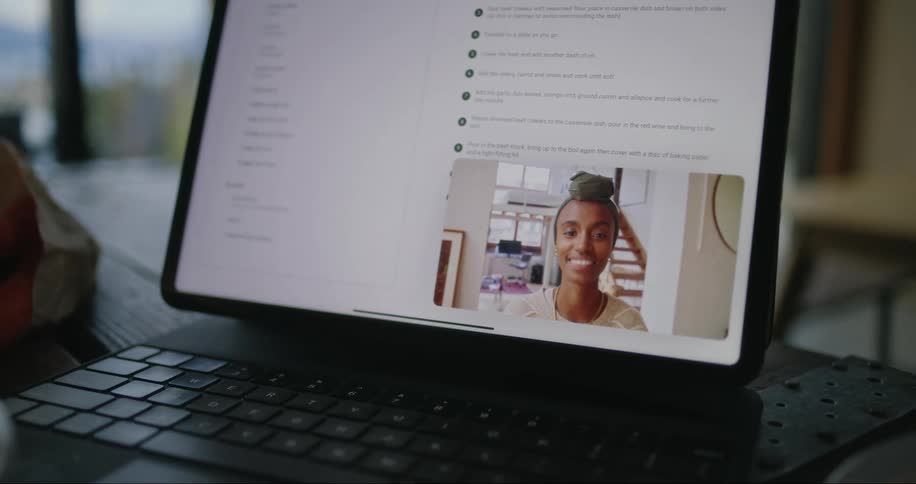 A black female talking on a laptop in a video call in a room with a window