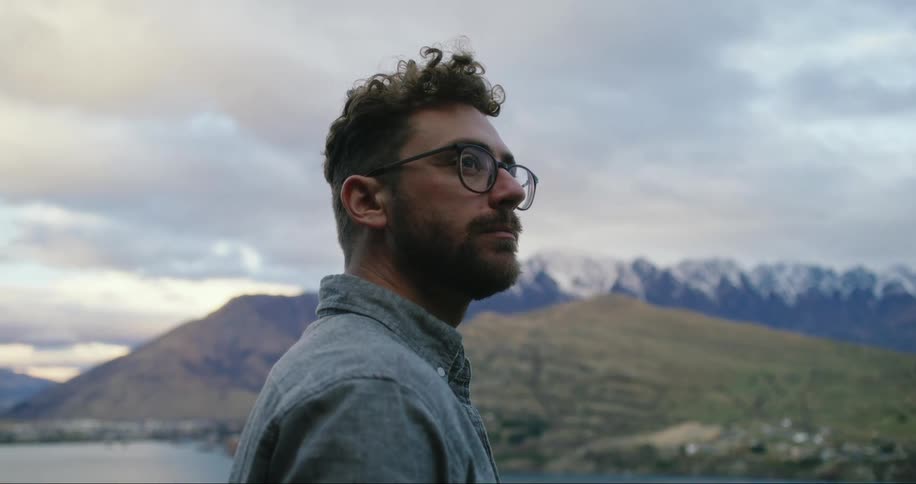 Man having a glass of wine facing a lake with mountains