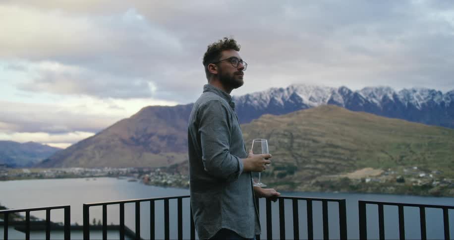 A man drinking wine on the balcony while enjoying the view of the surroundings