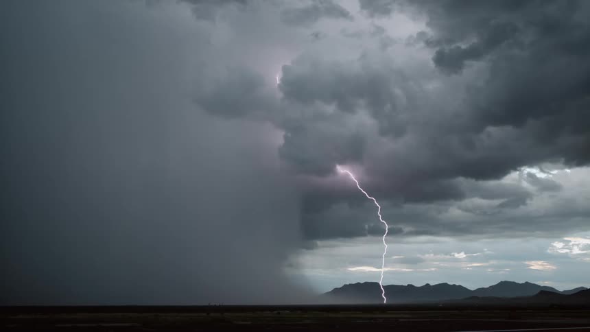 A dark and stormy sky with a lot of streak lightning near mountains and the desert