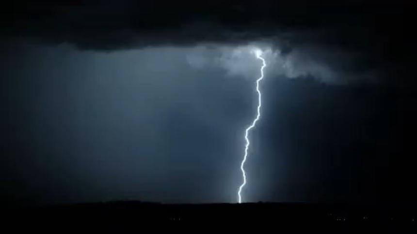 Lightning striking down and lighting up the dark night sky shining light on mountains on the horizon