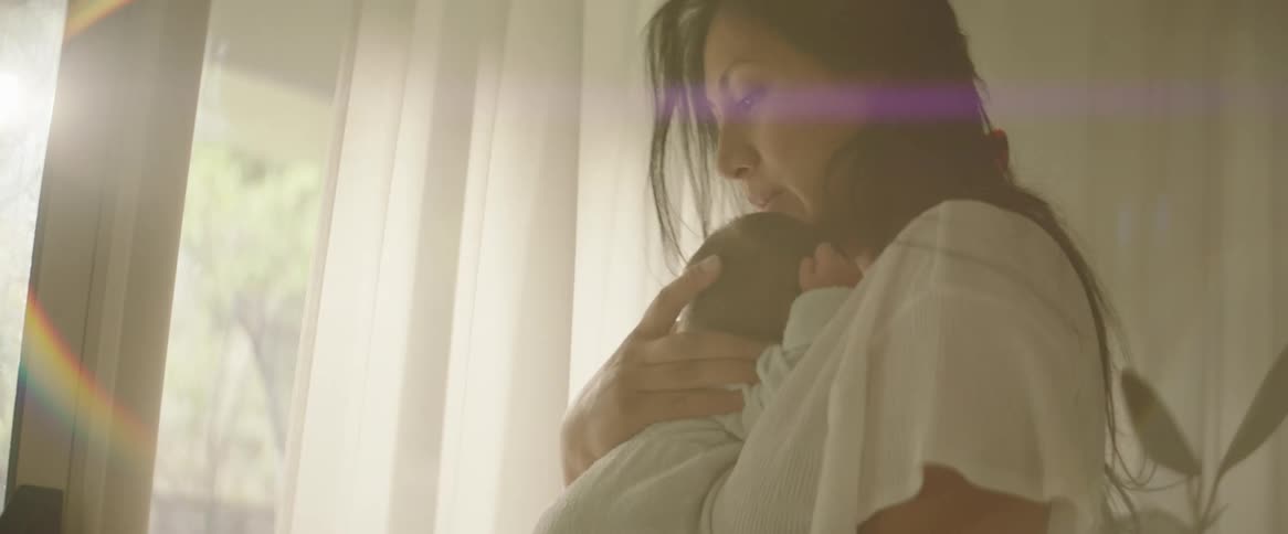 A mother cradles her baby rocking back and forth