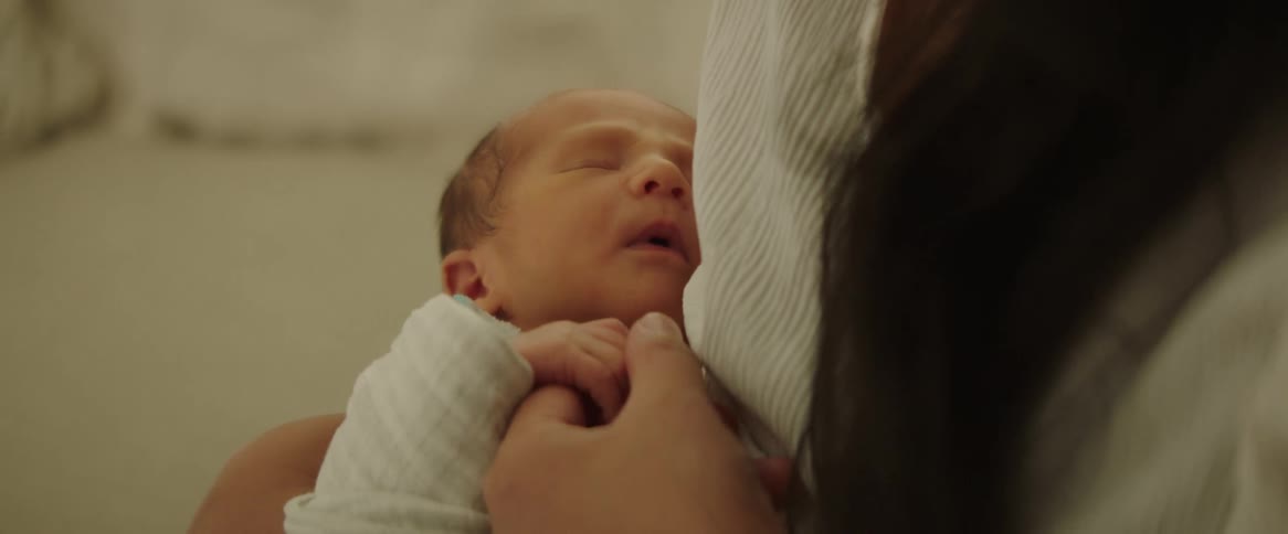A mother is rocking her baby and rubbing the babys hand