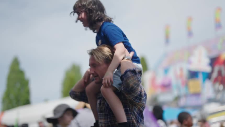 A man lifts a girl onto his shoulders and they both laugh happily