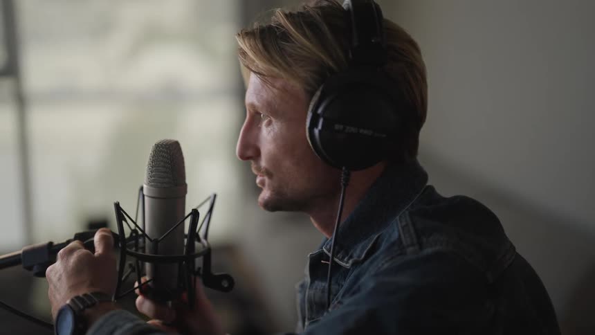 Man in the studio wearing headset setting up the microphone