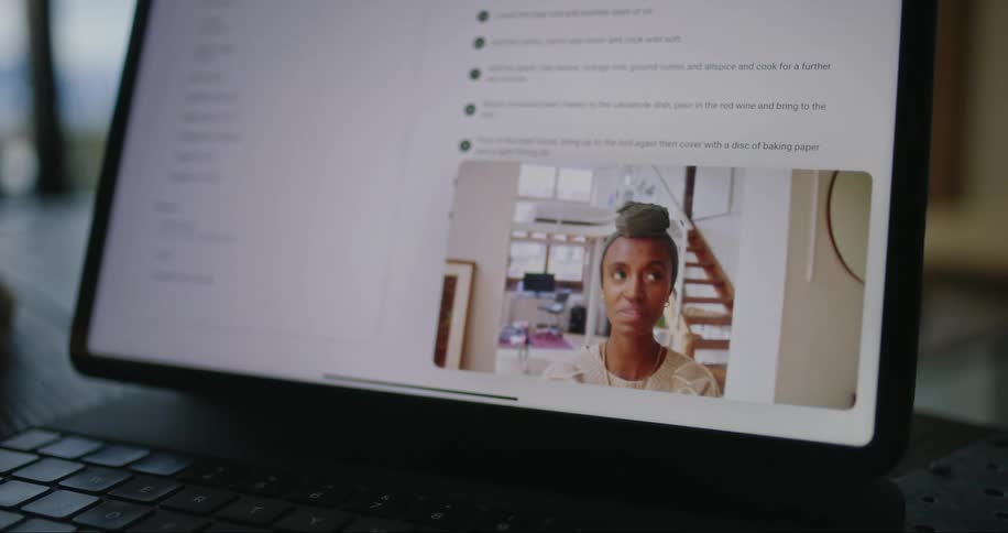 A black woman seen through a computer screen laughing and talking