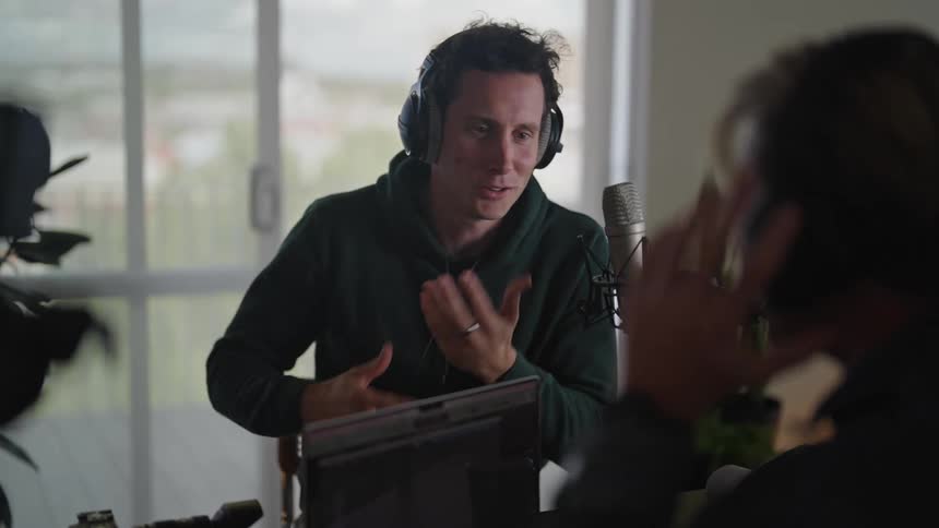 Men chatting at a table with a computer and microphone
